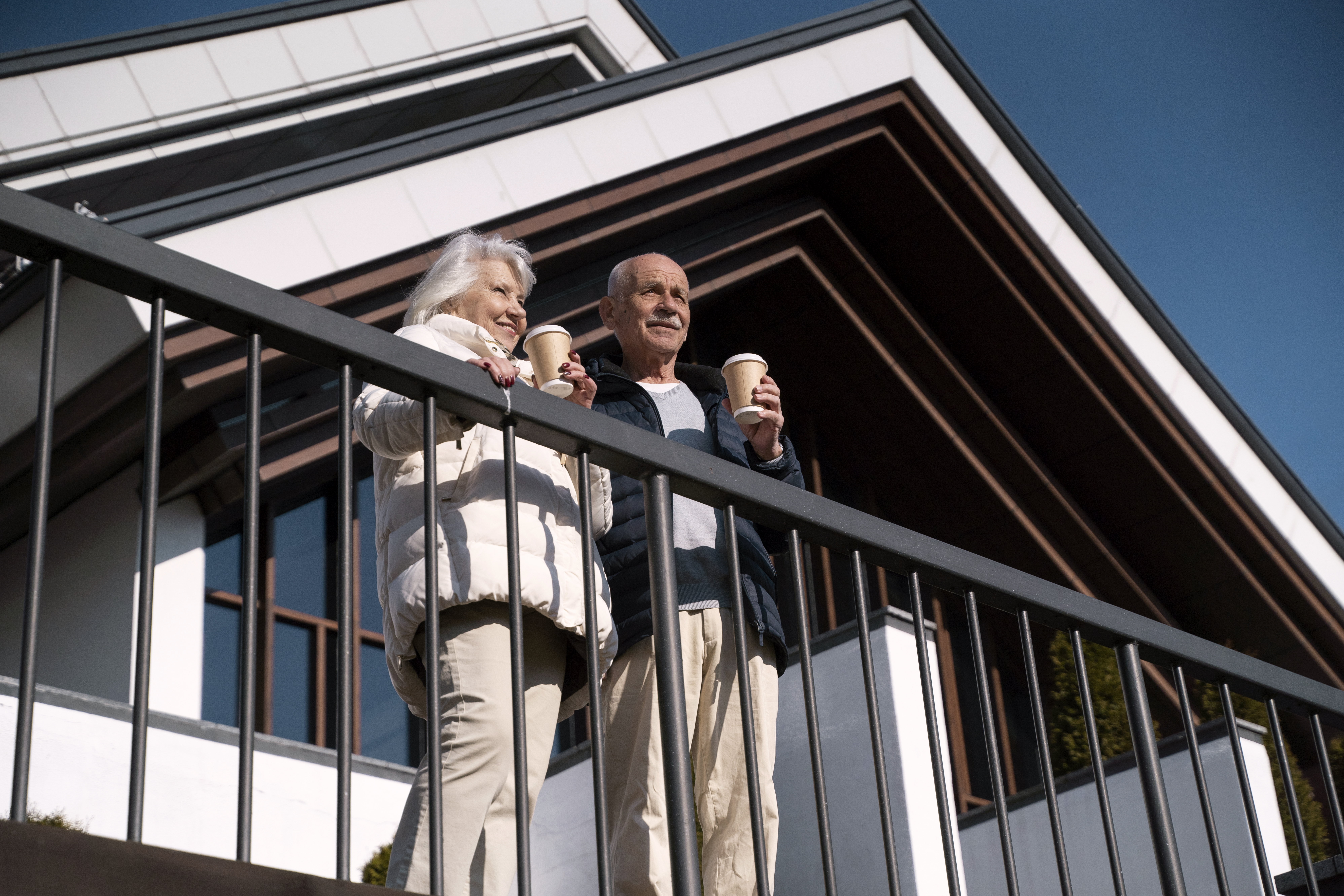 low-angle-smiley-senior-couple-with-coffee-cups